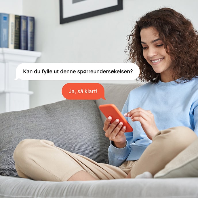 En jente som sitter på en sofa og svarer på en spørreundersøkelse på mobiltelefonen sin