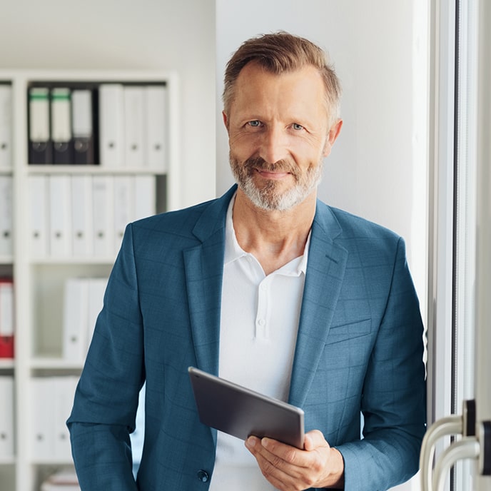 Mężczyzna z niebieskiej marynarce i tabletem w ręce.