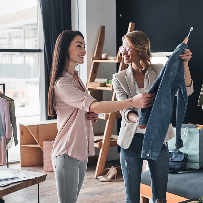 Sprzedawczyni pokazuje ubranie klientce, aby mogła dotknąć materiału.