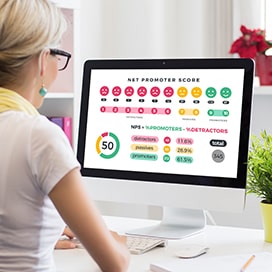 Kobieta siedząca przy komputerze i analizująca wskaźnik NPS